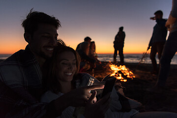 Image showing Couple enjoying bonfire with friends on beach