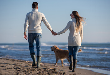 Image showing couple with dog having fun on beach on autmun day