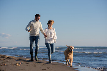 Image showing couple with dog having fun on beach on autmun day