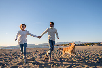 Image showing couple with dog having fun on beach on autmun day