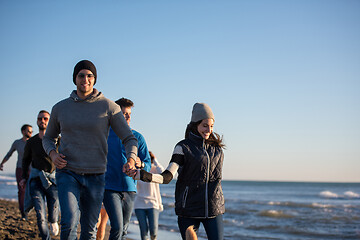 Image showing Group of friends running on beach during autumn day