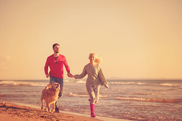 Image showing couple with dog having fun on beach on autmun day