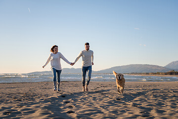 Image showing couple with dog having fun on beach on autmun day