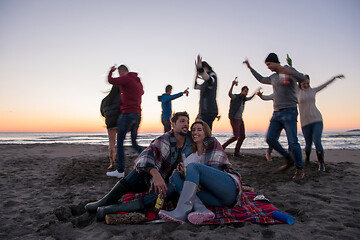 Image showing Couple enjoying with friends at sunset on the beach