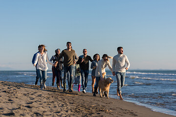 Image showing Group of friends running on beach during autumn day