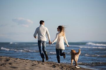 Image showing couple with dog having fun on beach on autmun day