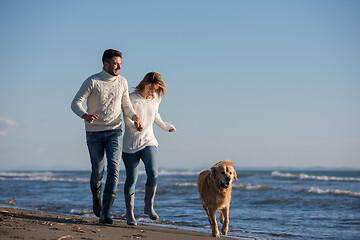 Image showing couple with dog having fun on beach on autmun day