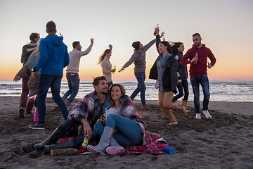 Image showing Couple enjoying with friends at sunset on the beach