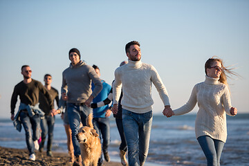 Image showing Group of friends running on beach during autumn day