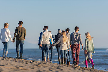 Image showing Group of friends running on beach during autumn day