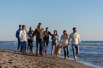 Image showing Group of friends running on beach during autumn day