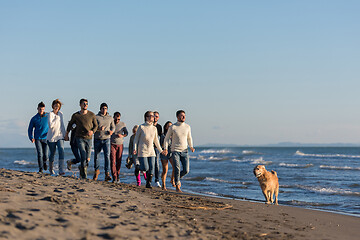 Image showing Group of friends running on beach during autumn day