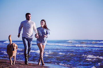 Image showing couple with dog having fun on beach on autmun day