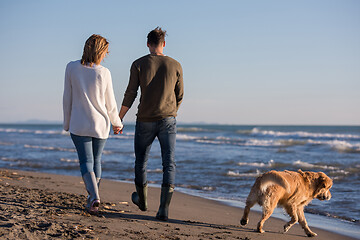 Image showing couple with dog having fun on beach on autmun day