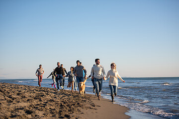 Image showing Group of friends running on beach during autumn day