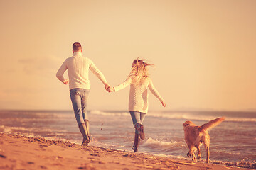 Image showing couple with dog having fun on beach on autmun day