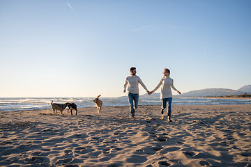 Image showing couple with dog having fun on beach on autmun day