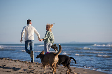 Image showing couple with dog having fun on beach on autmun day