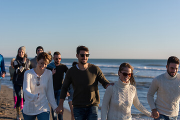 Image showing Group of friends running on beach during autumn day