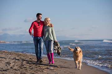 Image showing couple with dog having fun on beach on autmun day