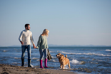 Image showing couple with dog having fun on beach on autmun day