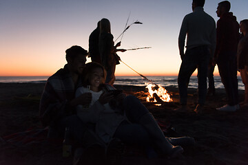 Image showing Couple enjoying bonfire with friends on beach