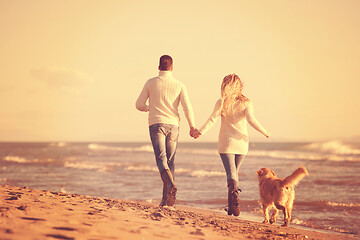 Image showing couple with dog having fun on beach on autmun day