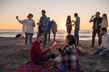 Image showing Couple enjoying with friends at sunset on the beach