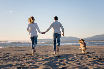 Image showing couple with dog having fun on beach on autmun day