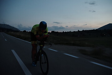 Image showing triathlon athlete riding bike at night