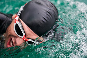 Image showing triathlon athlete swimming on lake wearing wetsuit