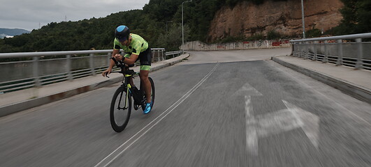 Image showing triathlon athlete riding a bike on morning training