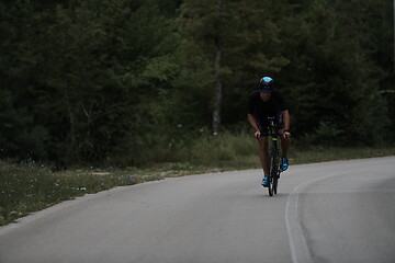 Image showing triathlon athlete riding a bike wearing black