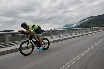 Image showing triathlon athlete riding a bike on morning training