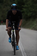 Image showing triathlon athlete riding a bike wearing black