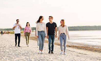 Image showing happy friends walking along summer beach