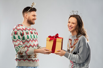 Image showing happy couple in christmas sweaters with gift box