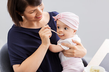 Image showing middle-aged mother feeding baby daughter at home