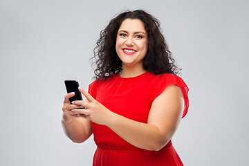 Image showing happy woman in red dress using smartphone