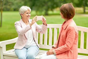 Image showing senior woman photographing her friend at park