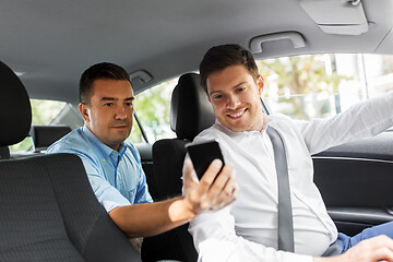 Image showing male passenger showing smartphone to car driver