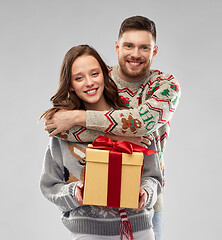 Image showing happy couple in christmas sweaters with gift box