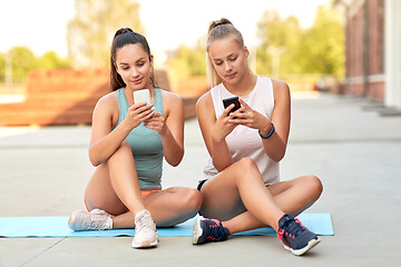 Image showing sporty women or friends with smartphone on rooftop