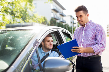 Image showing car driving instructor with clipboard and driver