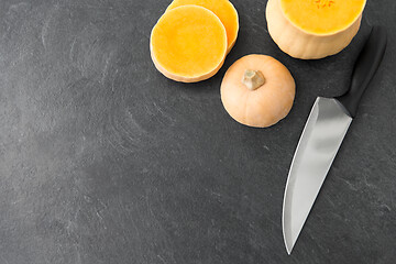 Image showing cut pumpkin and kitchen knife on stone background