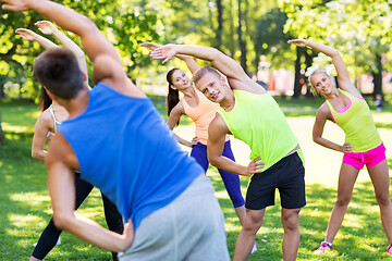 Image showing group of happy people exercising at summer park