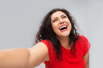 Image showing happy woman in red dress taking selfie