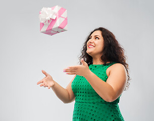 Image showing happy woman in green dress playing with gift box