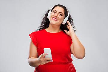 Image showing woman in headphones listens to music on smartphone