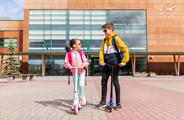 Image showing school children with backpacks riding scooters